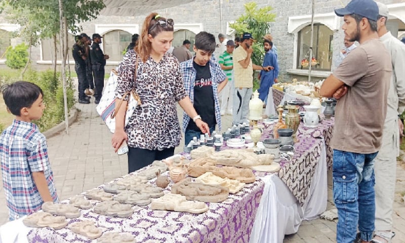 Visitors look at artifacts displayed at Gandhara Art Village during Vaisakh festival in Taxila on Sunday. — Dawn Visitors look at artifacts displayed at Gandhara Art Village during Vaisakh festival in Taxila on Sunday. — Dawn