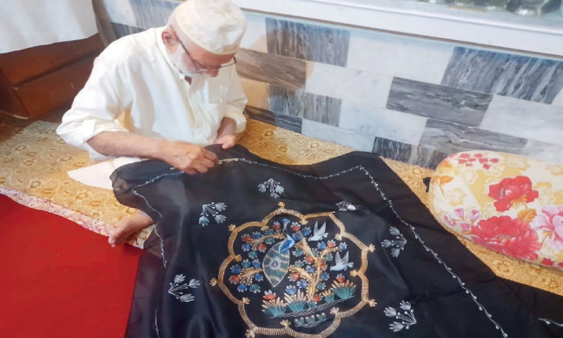 Riaz Ahmad makes a design on a tablecloth. — Dawn Riaz Ahmad makes a design on a tablecloth. — Dawn