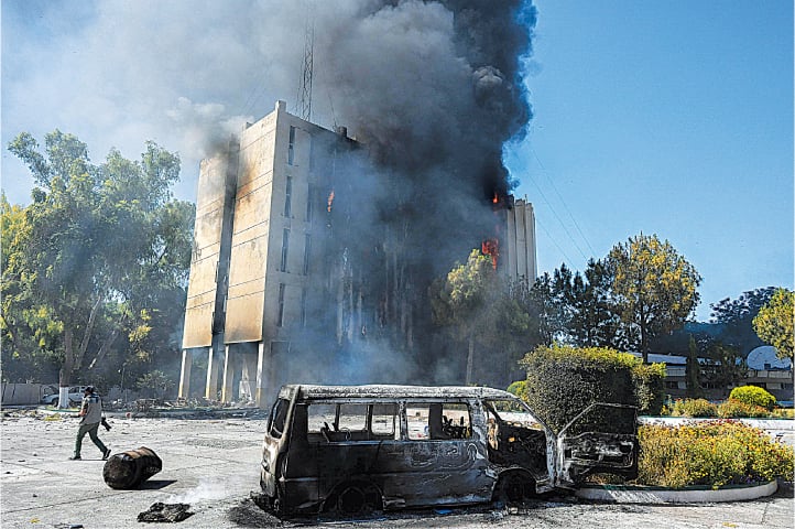 PESHAWAR: Black smoke billows from the Radio Pakistan building set ablaze by the PTI activists, on Wednesday.—AFP