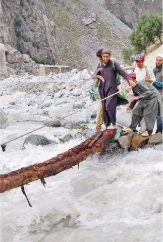 People use a tree trunk to cross Kandia River. — Dawn
