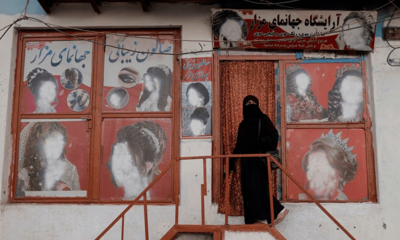 A woman wearing a niqab enters a beauty salon where the ads of women have been defaced by a shopkeeper in Kabul, Afghanistan on October 6, 2021. &mdash; Reuters