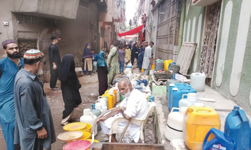 A MAN fills up with water the buckets, cans, dispenser bottles etc brought to him by residents of Agra Taj Colony. The locality in Lyari has been facing a severe shortage of water for long.—PPI