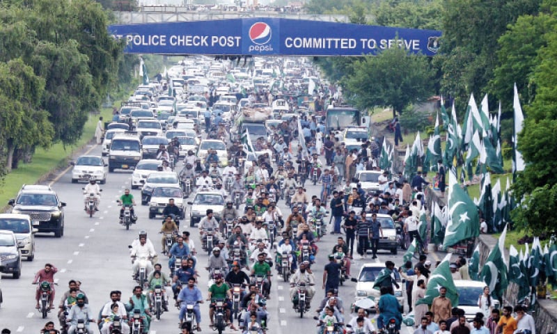 People travelling in vehicles wave national flags on Islamabad Expressway on Monday. &mdash; White Star