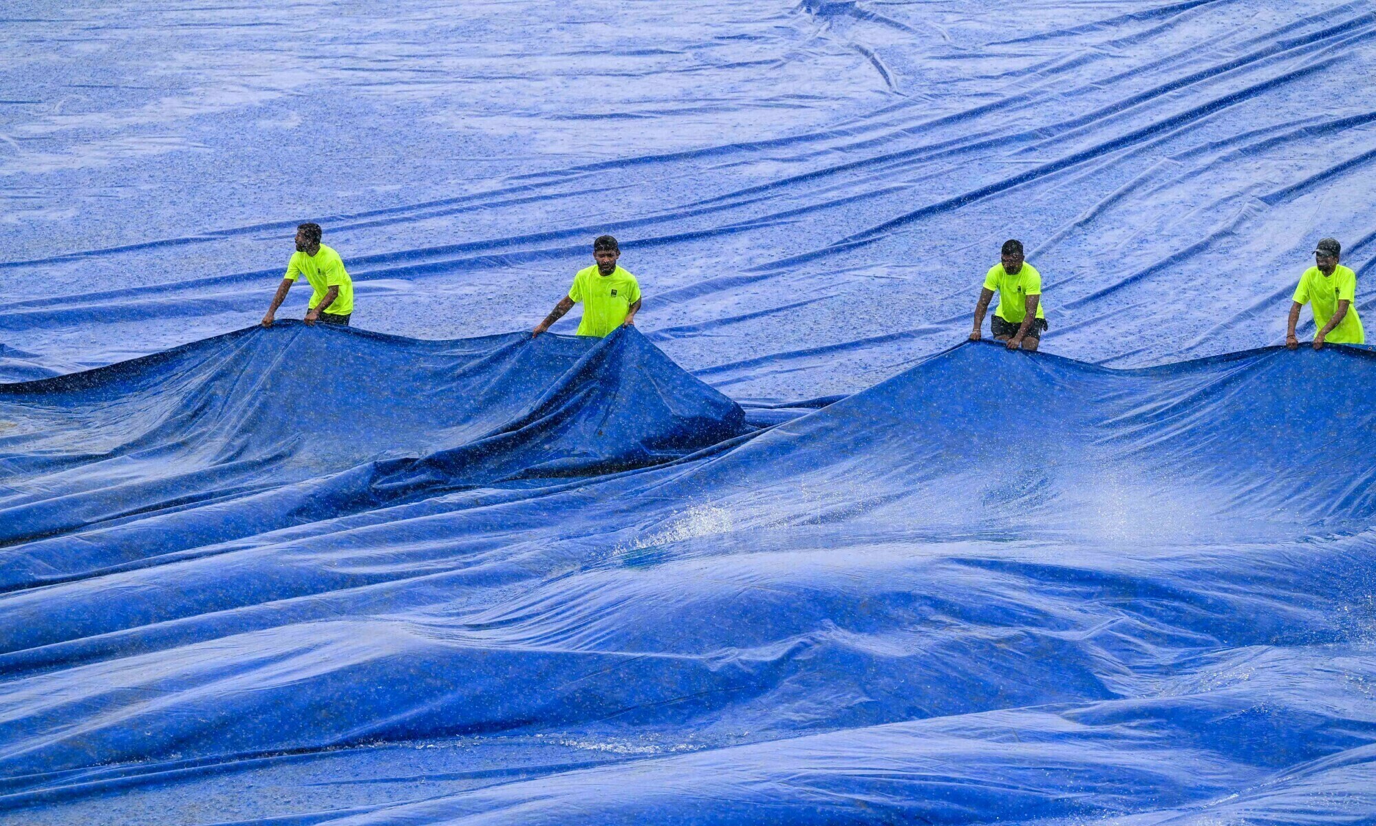 Members of ground staff cover the pitch as rain stops the second day play of the second and final cricket Test match between Pakistan and Sri Lanka at the Sinhalese Sports Club (SSC) Ground in Colombo on July 25. &mdash; AFP