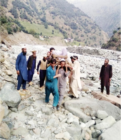 Villagers shift a patient from Dubair to a health facility in Lower Kohistan. — Dawn