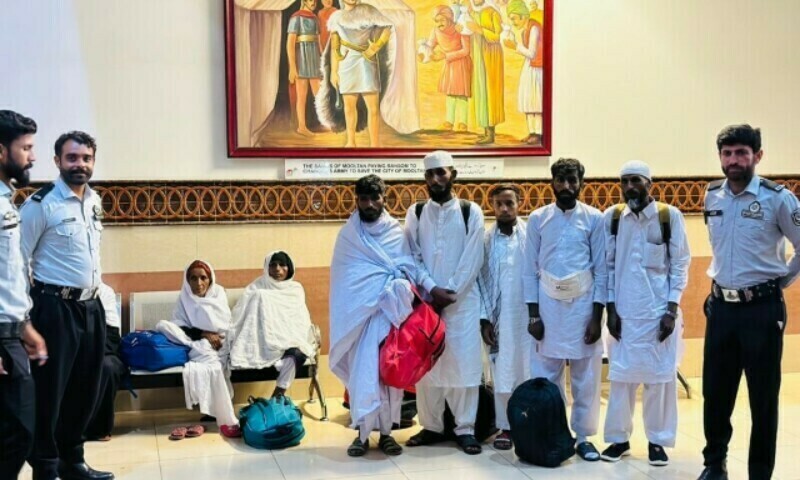 Beggars offloaded from a Saudi Arabia-bound flight pose for a photograph with FIA officials at the Multan airport. — FIA