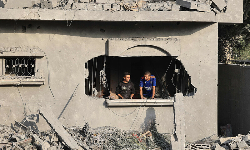 Palestinians look out a window in a damaged building after Israeli strikes on Rafah in the southern Gaza Strip on October 22. &mdash; AFP
