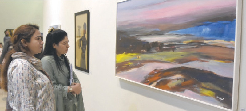 Women watch a painting at the exhibition held at PNCA on Thursday. — Photo by Tanveer Shahzad