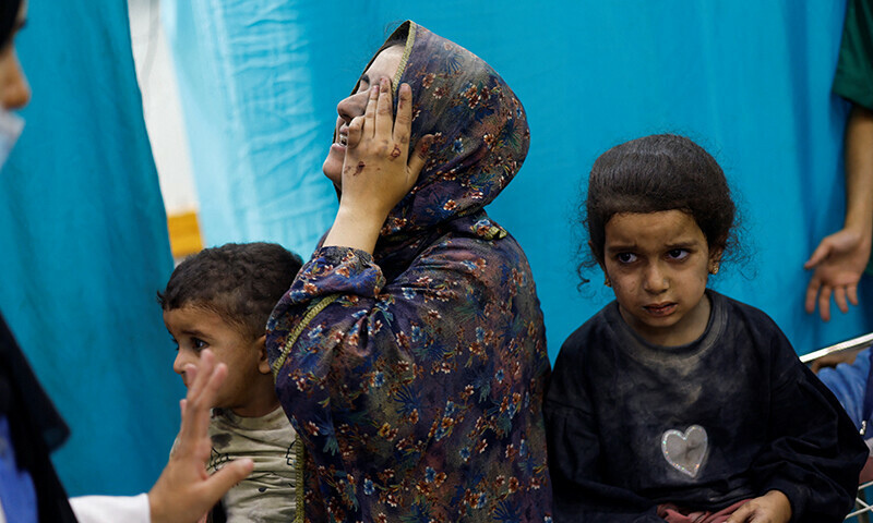 A woman reacts while sitting with Palestinian children wounded in Israeli strikes waiting to receive treatment at Nasser hospital in Khan Younis in the southern Gaza Strip November 12, 2023.&mdash;Reuters