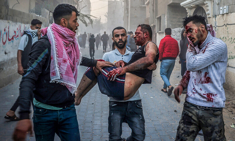 A Palestinian man carries an injured man as people flee following an Israeli strike in Rafah in the southern Gaza Strip on November 23, 2023, amid ongoing battles between Israel and the Palestinian fighter group Hamas.&mdash;AFP