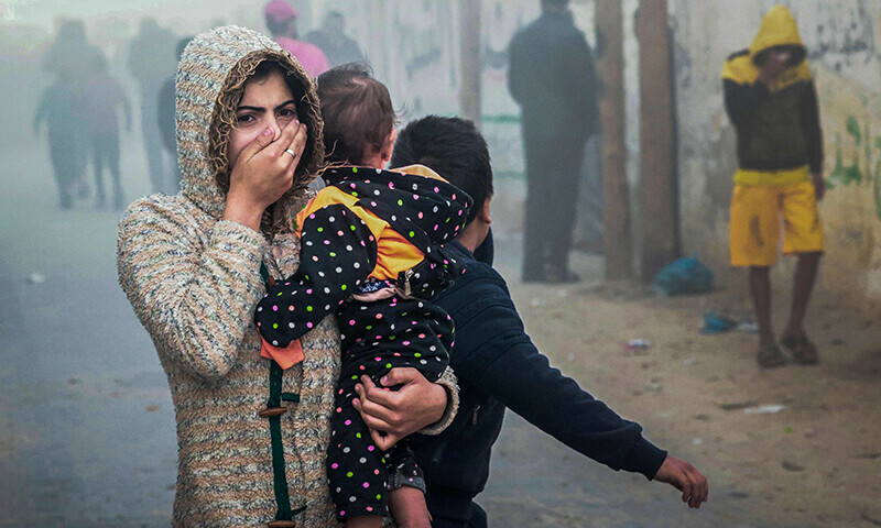A woman holding a child flees following an Israeli strike in Rafah in the southern Gaza Strip on November 23, 2023, amid ongoing battles between Israel and the Palestinian fighter group Hamas.&mdash;AFP)