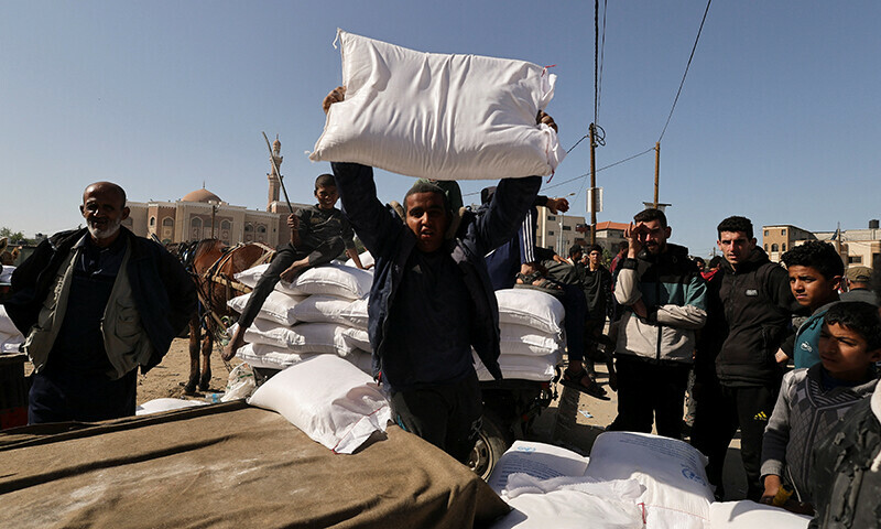 A man holds a flour bag, as Palestinians gather to receive flour distributed by UNRWA, amid the ongoing Israel&rsquo;s bombardment in Rafah, in the southern Gaza Strip on November 23.&mdash;Reuters
