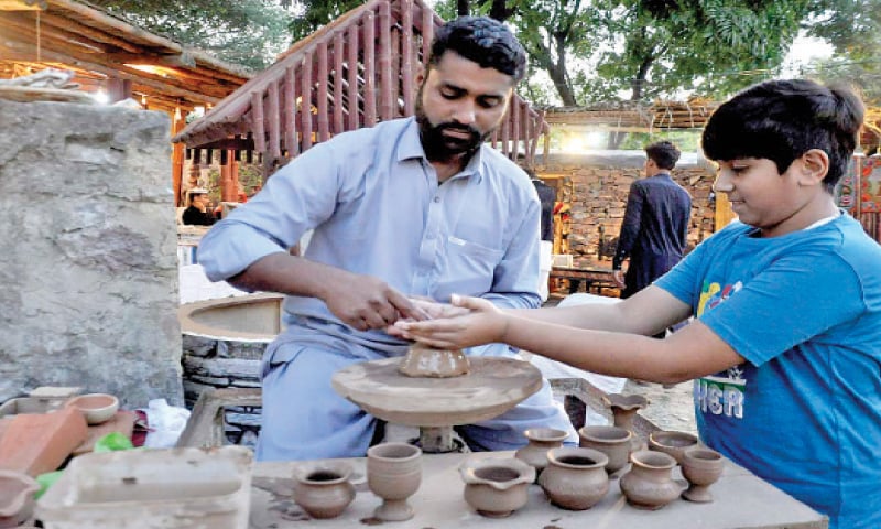 A potter helps a boy give shape to clay at Lok Virsa on Saturday. &mdash; APP