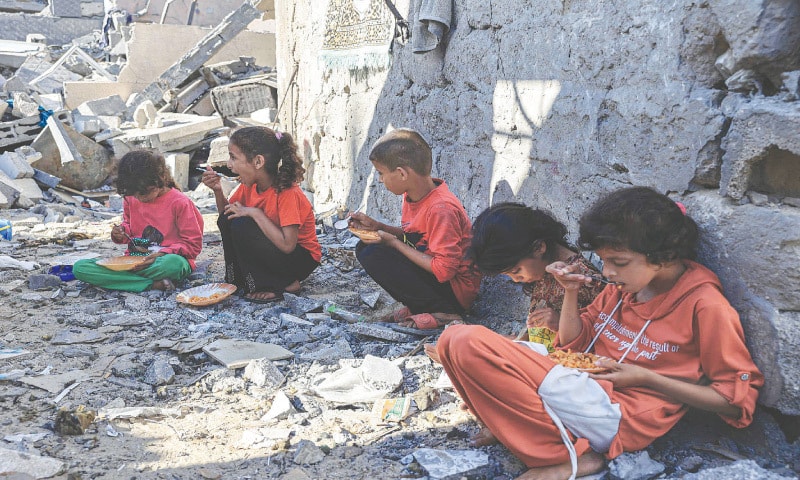 AMAL Al Robayaa’s children eat their meal amid the ruins of their family home which was destroyed in an Israeli strike in Rafah, southern Gaza Strip. Robayaa says the apartment block she lived in was destroyed by an Israeli bombardment on Oct 7. She now sleeps with other family members at a UN school in Rafah, but returns to her home in the morning to face a daily struggle to find food and water.—AFP