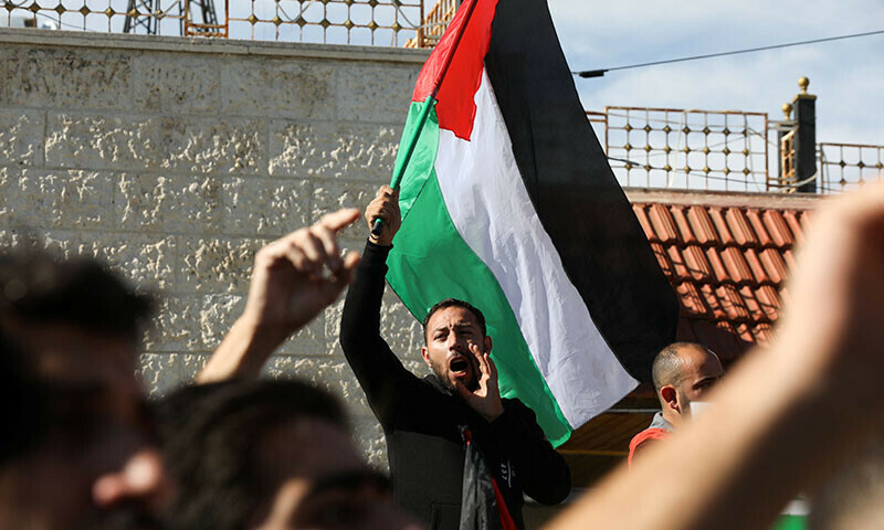 A man holds a Palestinian flag during a protest in support of Palestinians in Gaza, in Amman, Jordan December 8, 2023. &mdash; Reuters