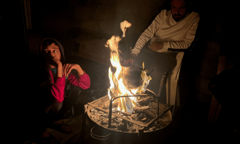 Palestinians sit around a fire during a power cut in Rafah, in the southern Gaza Strip December 11. &mdash; Reuters