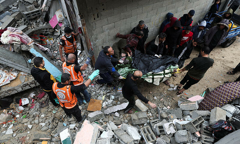 Palestinians carry a casualty at the site of Israeli strikes on houses in Khan Younis in the southern Gaza Strip, December 13, 2023. &mdash; Reuters