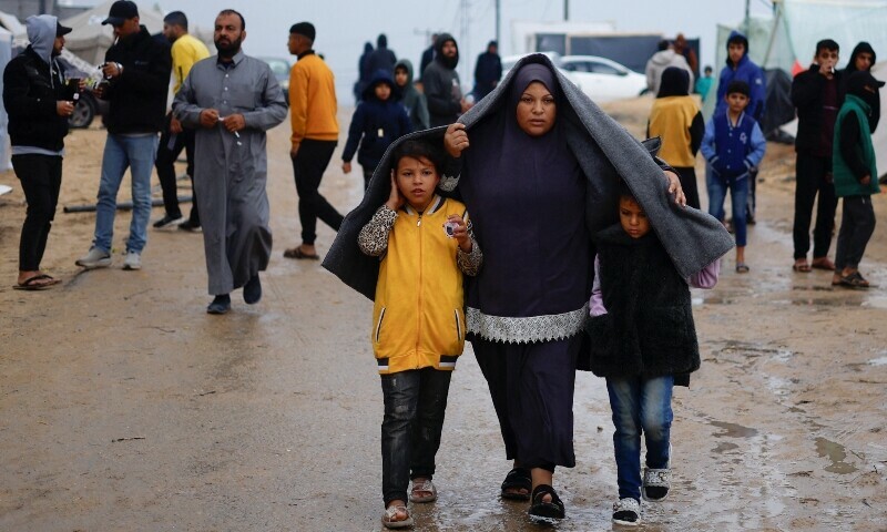 Displaced Palestinians, who fled their houses due to Israeli strikes, walk following heavy rains at tent camps, in Rafah, in the southern Gaza Strip December 13, 2023.&mdash;Reuters
