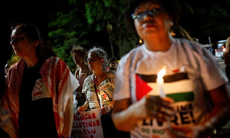 People hold candles during a vigil in tribute to Palestinian children in Gaza in Brazil on December 15, 2023 &mdash; Reuters