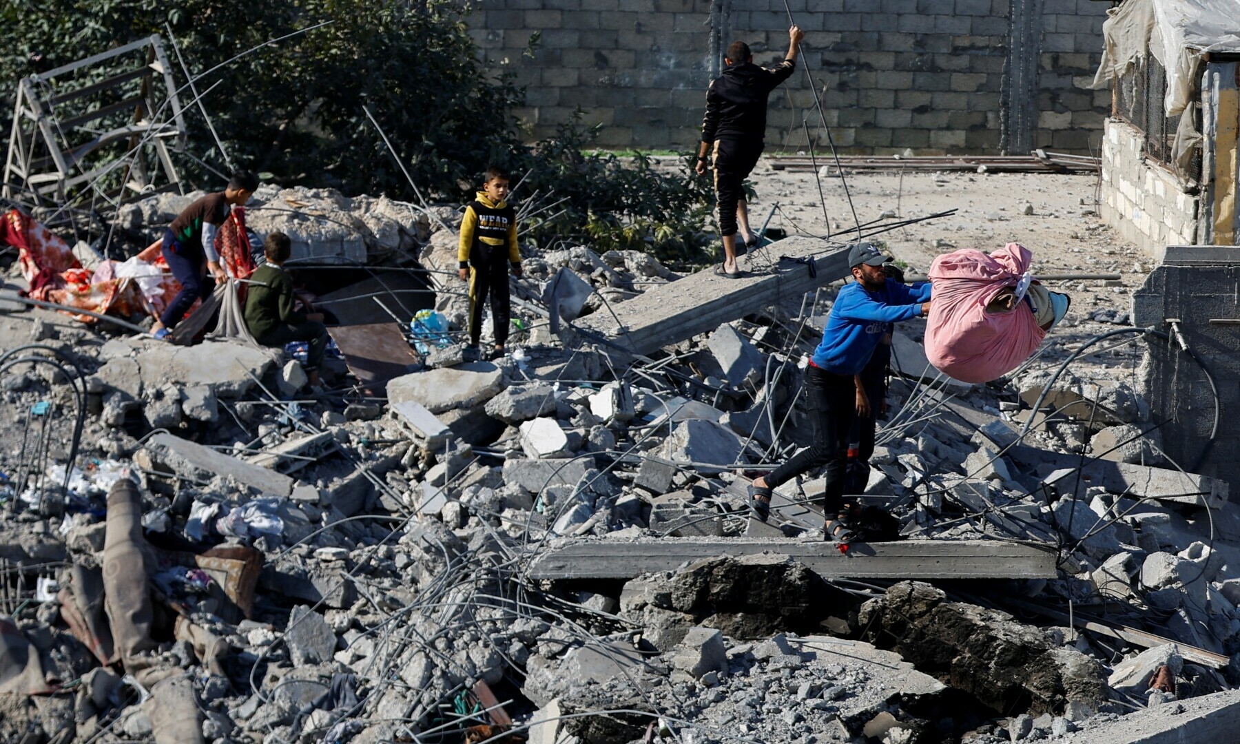  Palestinians inspect the site of an Israeli strike on a house in Rafah in the southern Gaza Strip on Dec 16, 2023. &mdash; Reuters 