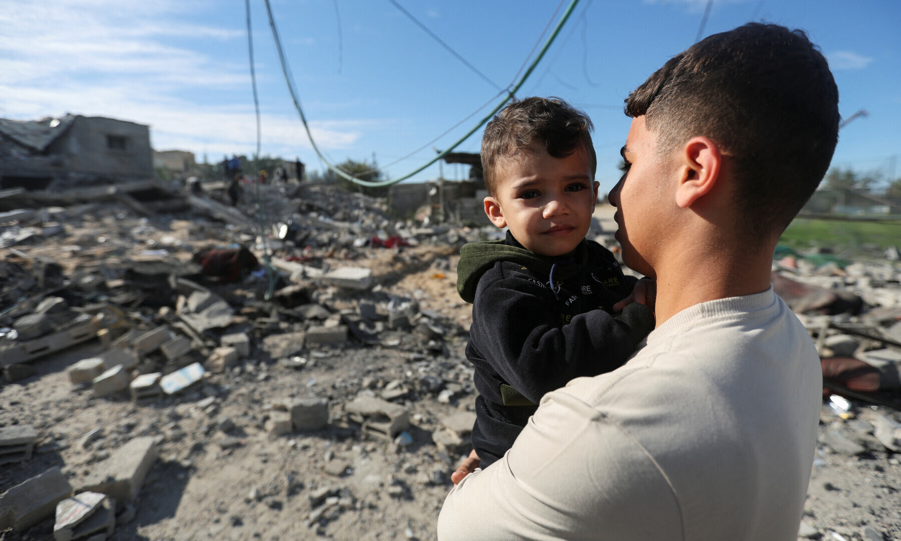  A Palestinian holds a child as they look on at the site of an Israeli strike on a house in Rafah in the southern Gaza Strip on Dec 16, 2023. &mdash; Reuters 