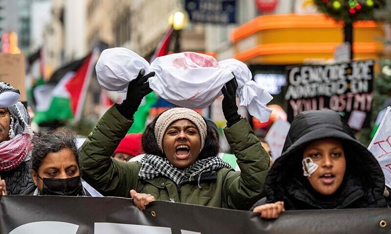 A demonstrator marches with a replica of a dead Palestinian child wrapped in a burial shroud at a rally held by the Boston Coalition for Palestine, calling for a permanent ceasefire in Gaza on December 17, 2023. &mdash; AFP
