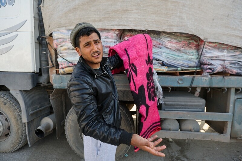 A man holds a blanket beside a truck carrying aid at the Rafah border in the southern Gaza Strip, December 18. &mdash; Reuters