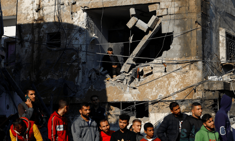 Palestinians look on at the site of an Israeli strike on a house in Rafah, in the southern Gaza Strip, December 19. &mdash; Reuters