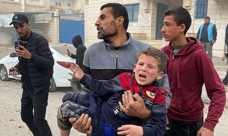 A Palestinian man carries a child, in the aftermath of an Israeli strike, amid the Israeli bombardment in Rafah, in the southern Gaza Strip, December 20, 2023.&mdash;Reuters