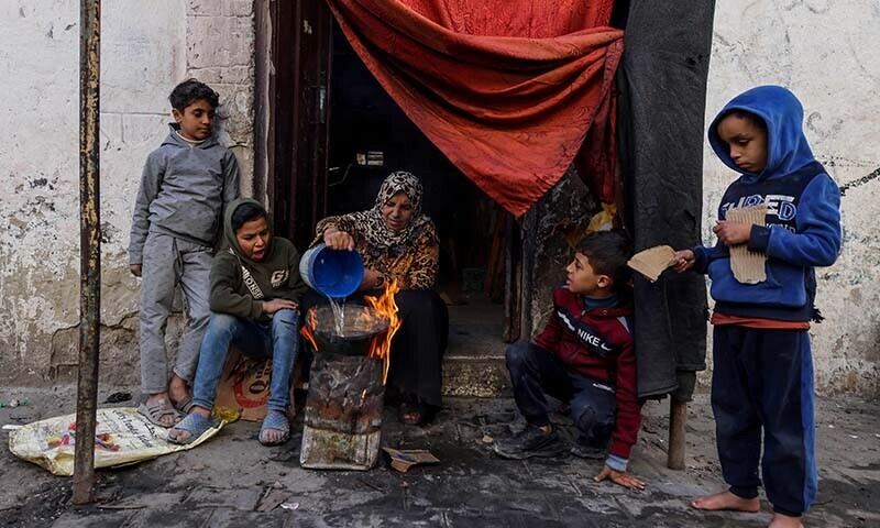 A Palestinian woman makes food outside a house in the southern Gaza Strip on December 22, 2023. &mdash; AFP