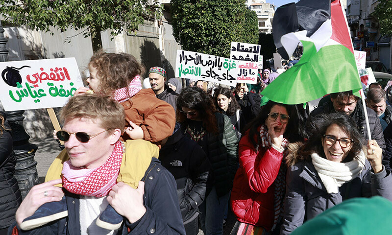 Demonstrators lift signs and the Palestinian flag during a rally after the Friday noon prayer in Ramallah city in the occupied West Bank on December 22, 2023. &mdash; AFP