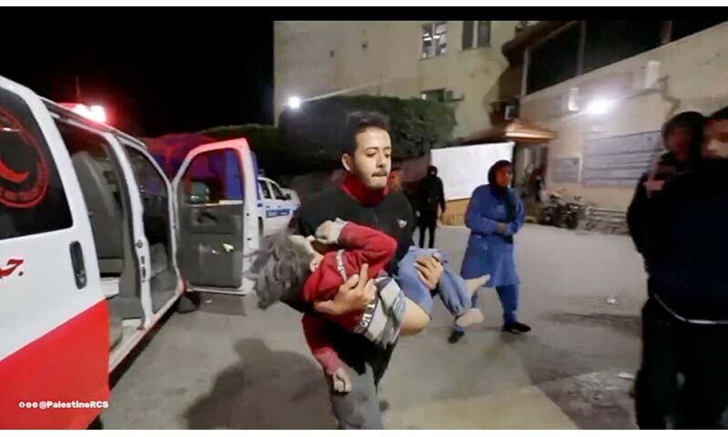 A member of the Palestine Red Crescent Society carries a Palestinian child as wounded Palestinians are rushed into a hospital following Israeli strikes at Deir al-Balah, Gaza in this screenshot taken from a handout video released on December 22, 2023 by Palestine Red Crescent Society &mdash; Reuters