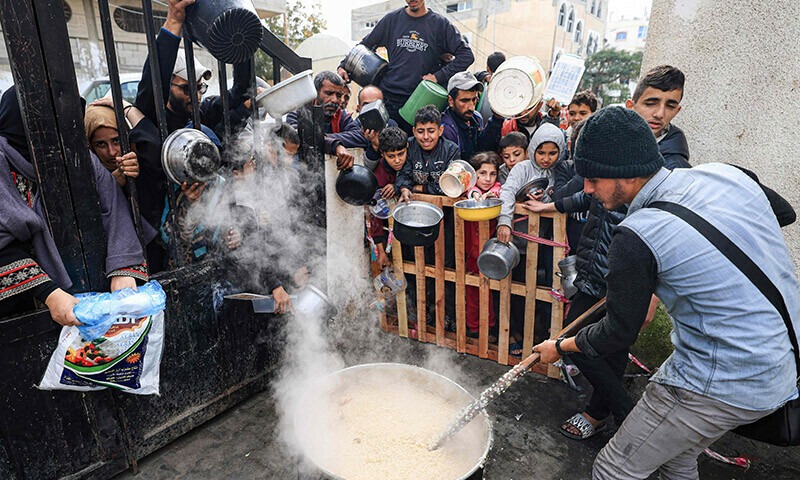 Palestinians wait to collect food at a donation point in a refugee camp in Rafah in the southern Gaza Strip on December 23, 2023. &mdash; AFP