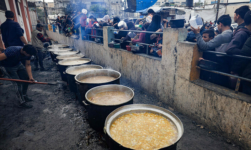 Palestinians wait to collect food at a donation point in a refugee camp in Rafah in the southern Gaza Strip on December 23, 2023. &mdash; AFP