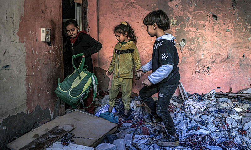 Children inspect items in the rubble in a room overlooking a building destroyed by Israeli bombardment in Rafah in the southern Gaza Strip on December 24, 2023&mdash;AFP