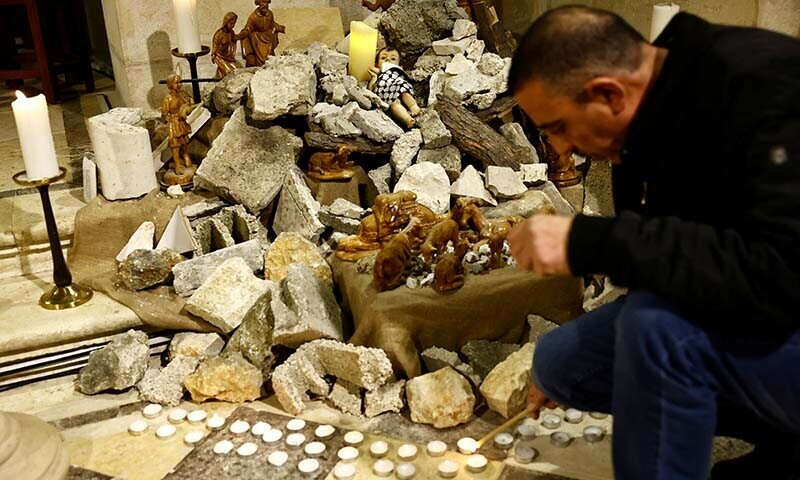 An installation shows a figure symbolizing baby Jesus lying amidst the rubble in a grotto ahead of Christmas at the Evangelical Lutheran Church, in Bethlehem, in the Israeli-occupied West Bank on December 24, 2023 &mdash; Reuters