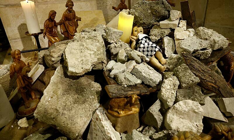 An installation shows a figure symbolizing baby Jesus lying amidst the rubble in a grotto ahead of Christmas at the Evangelical Lutheran Church, in Bethlehem, in the Israeli-occupied West Bank on December 24, 2023 &mdash; Reuters