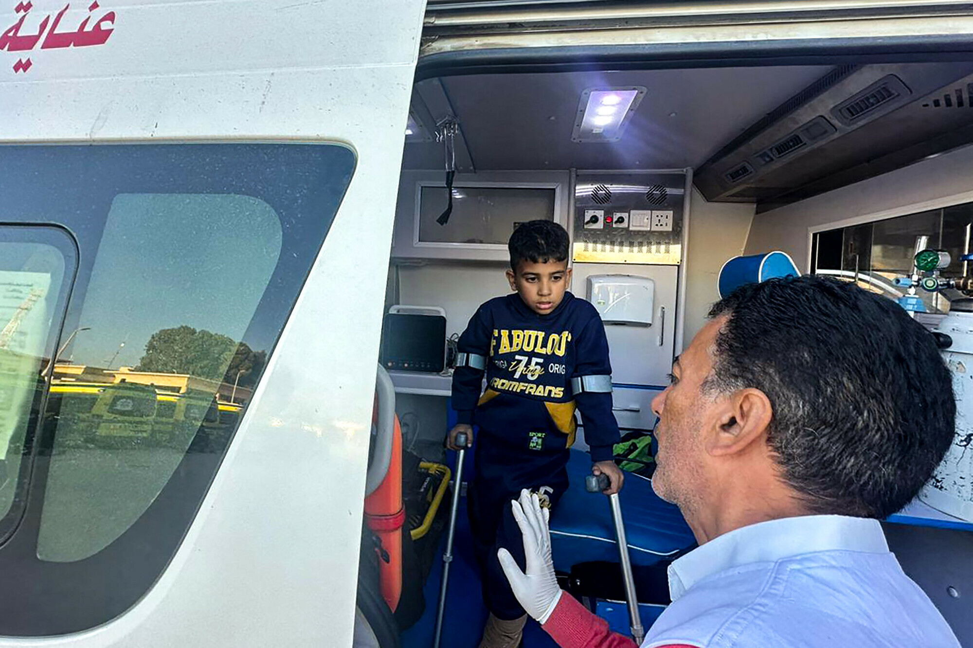 A wounded Palestinian child uses crutches out of an ambulance at the Rafah border crossing in Egypt after being evacuated from the Gaza Strip, on December 25. &mdash; AFP