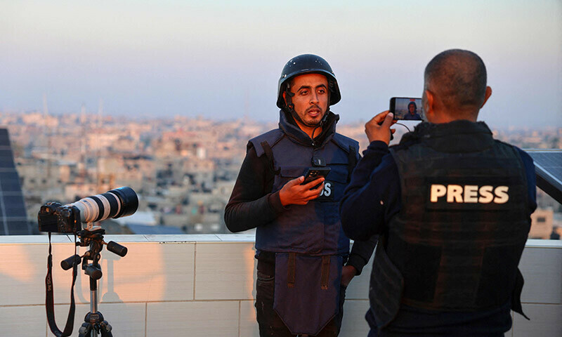 Palestinian journalist Hani al-Shaer uses a mobile phone to broadcast live in Rafah on the southern Gaza Strip on December 27, 2023. &mdash; AFP