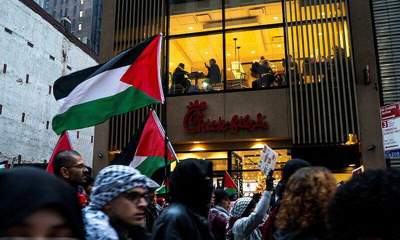 People in a restaurant watch as Pro-Palestinian demonstrators march demanding a ceasefire&nbsp;during a protest in New York City, US on December 28, 2023 &mdash; Reuters