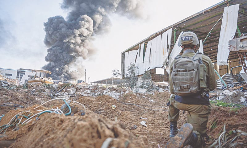 an Israeli soldier takes position as smoke billows from a building in Gaza Strip, on Tuesday.—AFP an Israeli soldier takes position as smoke billows from a building in Gaza Strip, on Tuesday.—AFP