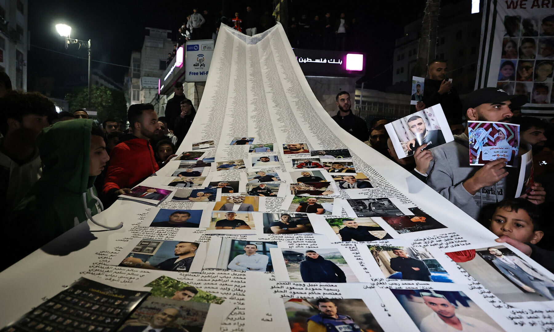  Demonstrators hold a huge banner with names of Palestinains as they protest in solidarity with Gaza in Ramallah, in the occupied West Bank on Jan 1, 2024. &mdash; AFP 
