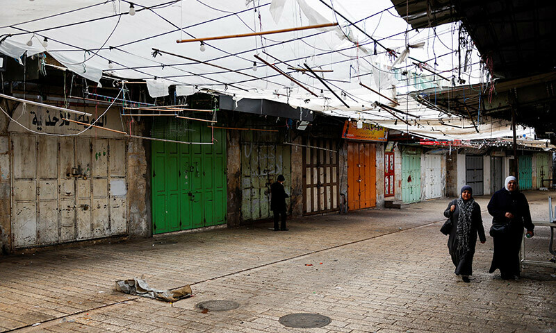 Palestinians walk past closed shops during a strike as a protest against the killing of senior Hamas official, Saleh al-Arouri, in Hebron in the Israeli-occupied West Bank January 3, 2024. &mdash; Reuters