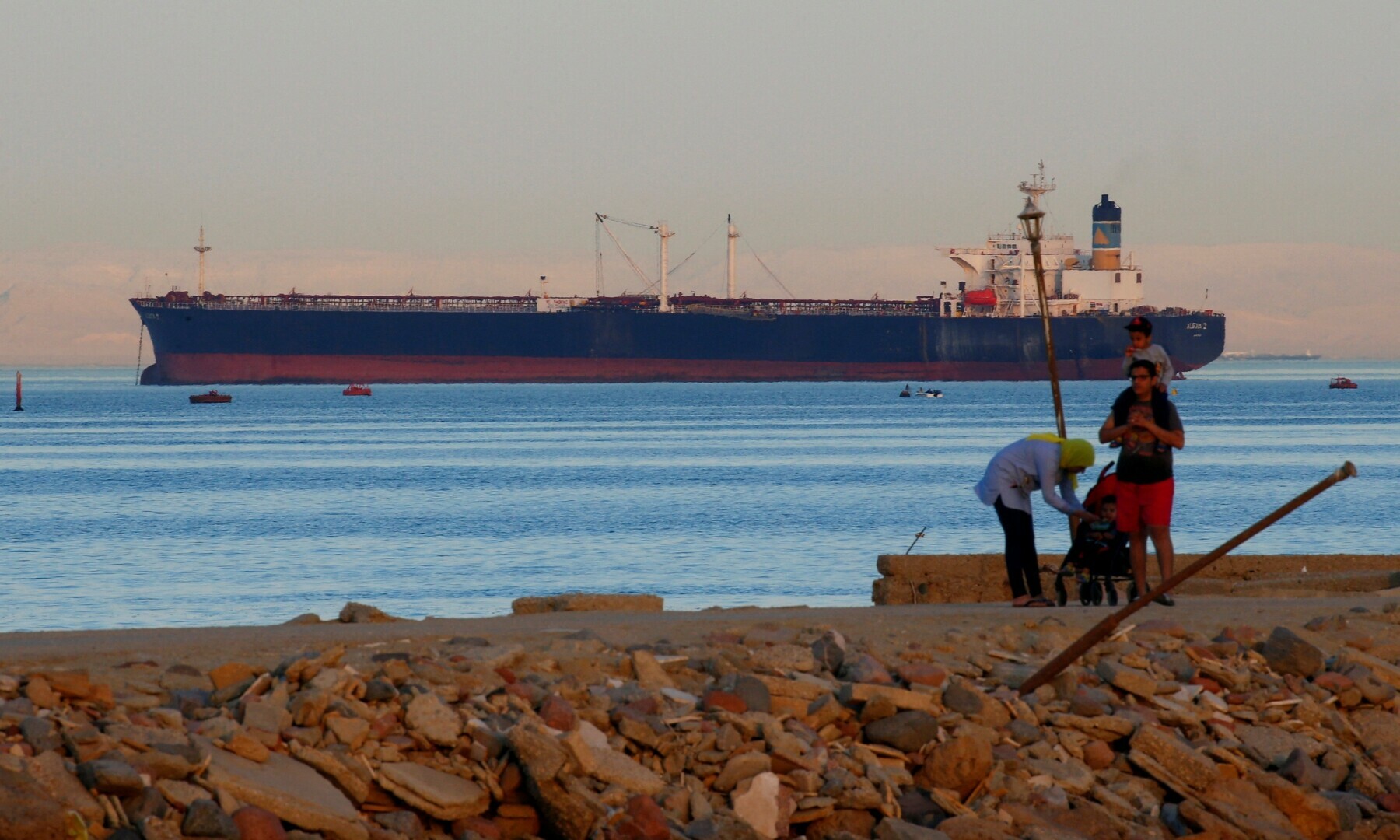  People walk on the beach as a container ship crosses the Gulf of Suez towards the Red Sea before entering the Suez Canal, in El Ain El Sokhna in Suez, east of Cairo, Egypt on April 24, 2017. &mdash; Reuters 