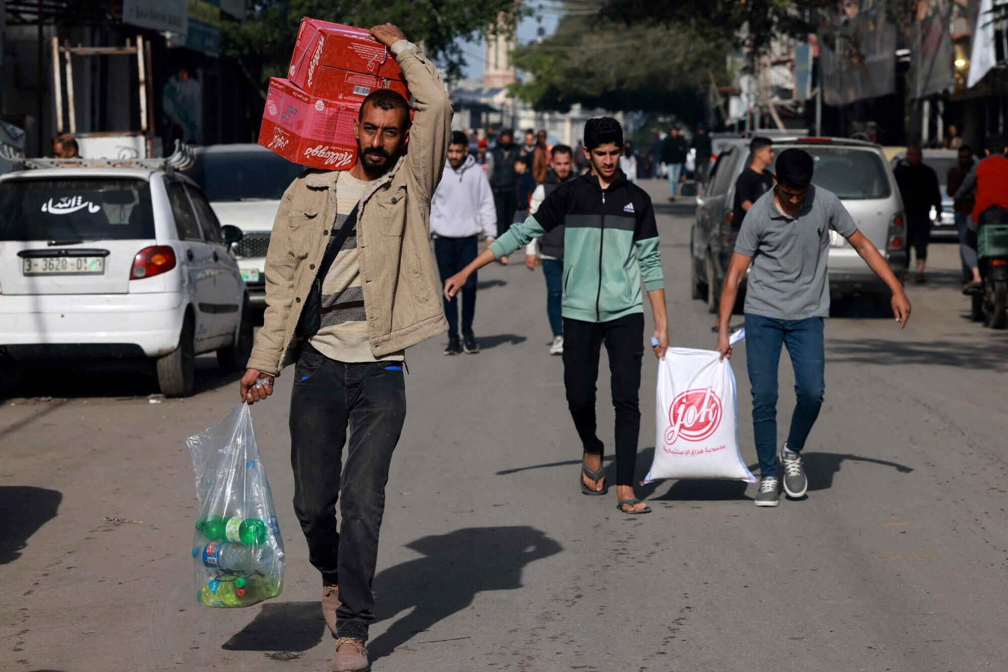  Palestinian men carry their shopping at a market in Rafah refugee camp in the Gaza Strip on Jan 8, 2024. &mdash; AFP 
