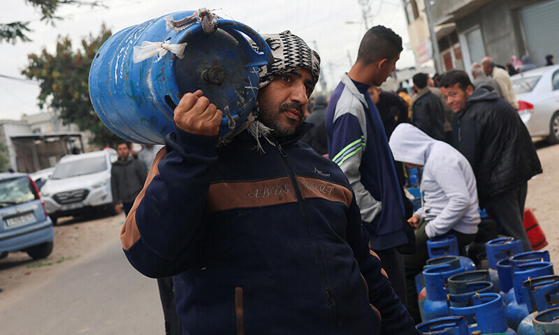 A man lifts a cylinder on his shoulders as Palestinians wait to fill their cylinders with cooking gas amid shortage, as the conflict between Israel and Hamas continues, in Rafah, in the southern Gaza Strip, January 11, 2024.&mdash;Reuters