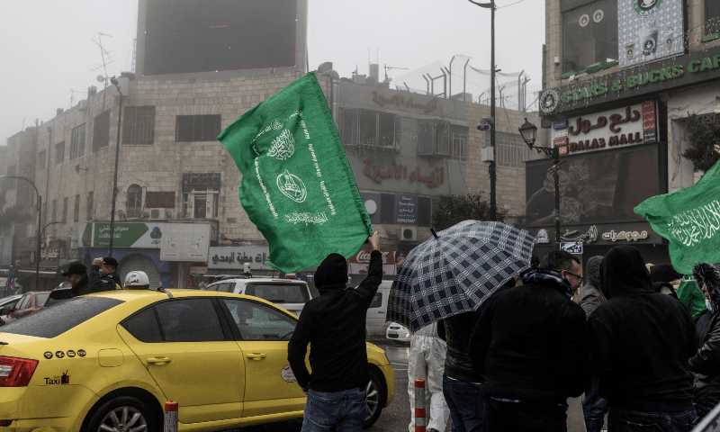  Protesters wave Hamas flags during a demonstration under the rain in support of the Palestinian resistance in Al-Manara Square in the West Bank city of Ramallah on Jan 12, 2024. &mdash; AFP 
