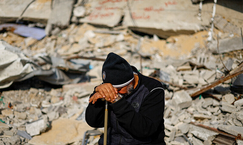 Ziad Mansour, a neighbour of the Abu Aweidah family, sits next to writing painted on a wall amid the rubble of the family&rsquo;s house, which was destroyed in a deadly Israeli strike in Rafah, Gaza Strip&mdash; Reuters