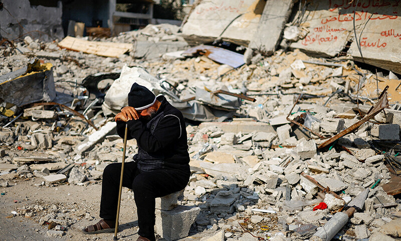 Ziad Mansour, a neighbour of the Abu Aweidah family, sits next to writing painted on a wall amid the rubble of the family&rsquo;s house, which was destroyed in a deadly Israeli strike in Rafah, Gaza Strip&mdash; Reuters