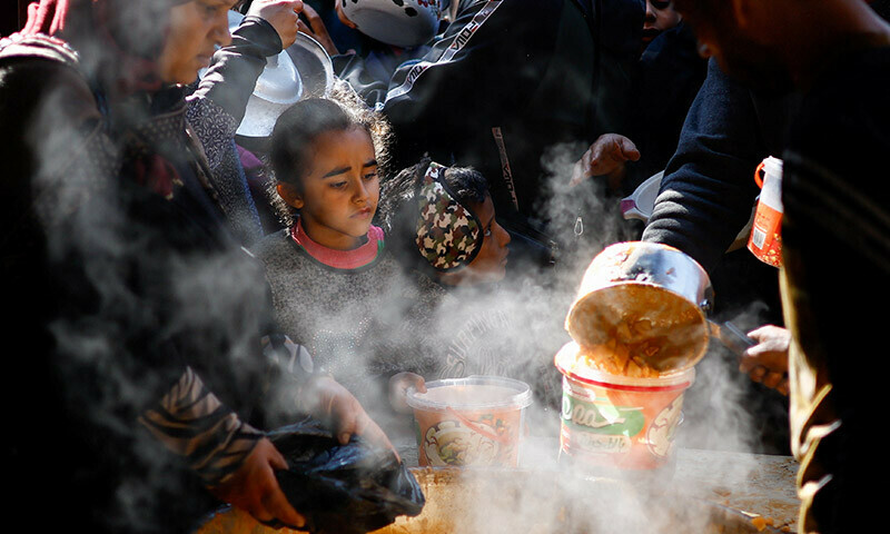 Palestinians wait to receive food cooked by a charity kitchen amid shortages of food supplies in Rafah in the southern Gaza Strip on January 16. &mdash; Reuters